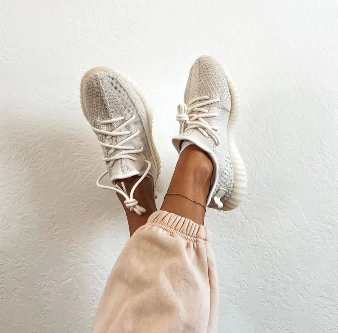 Close-up of stylish light gray sneakers worn with relaxed pants, perfect for casual outings in 2024.