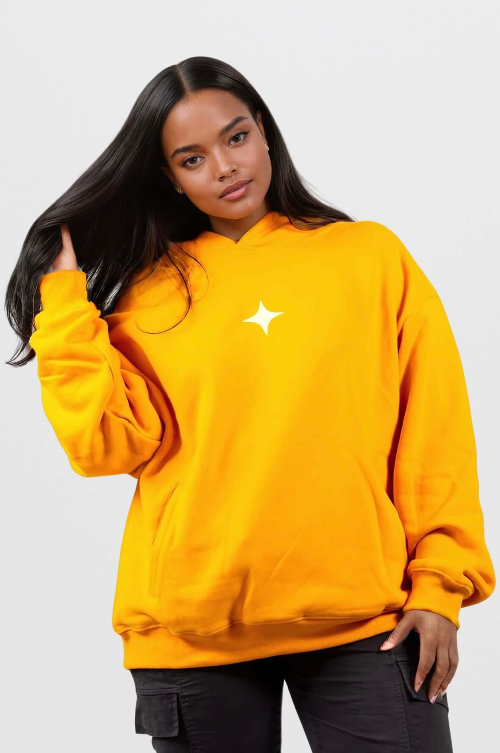 Woman wearing a bright yellow oversized hoodie with a star design, styled for a casual and comfortable look.