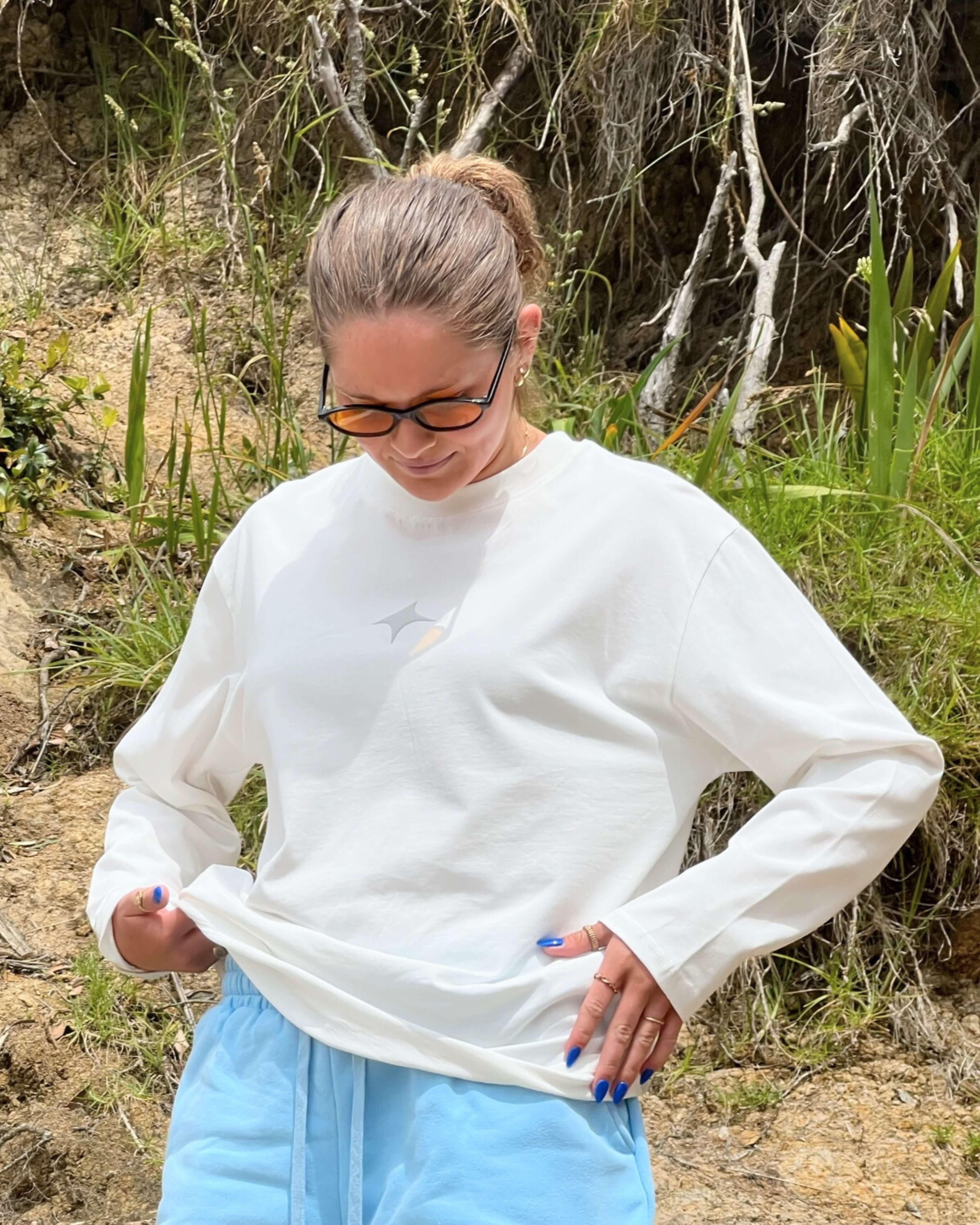 Woman wearing a Cloud White Long Sleeve Tee outdoors, showcasing comfort and style.
