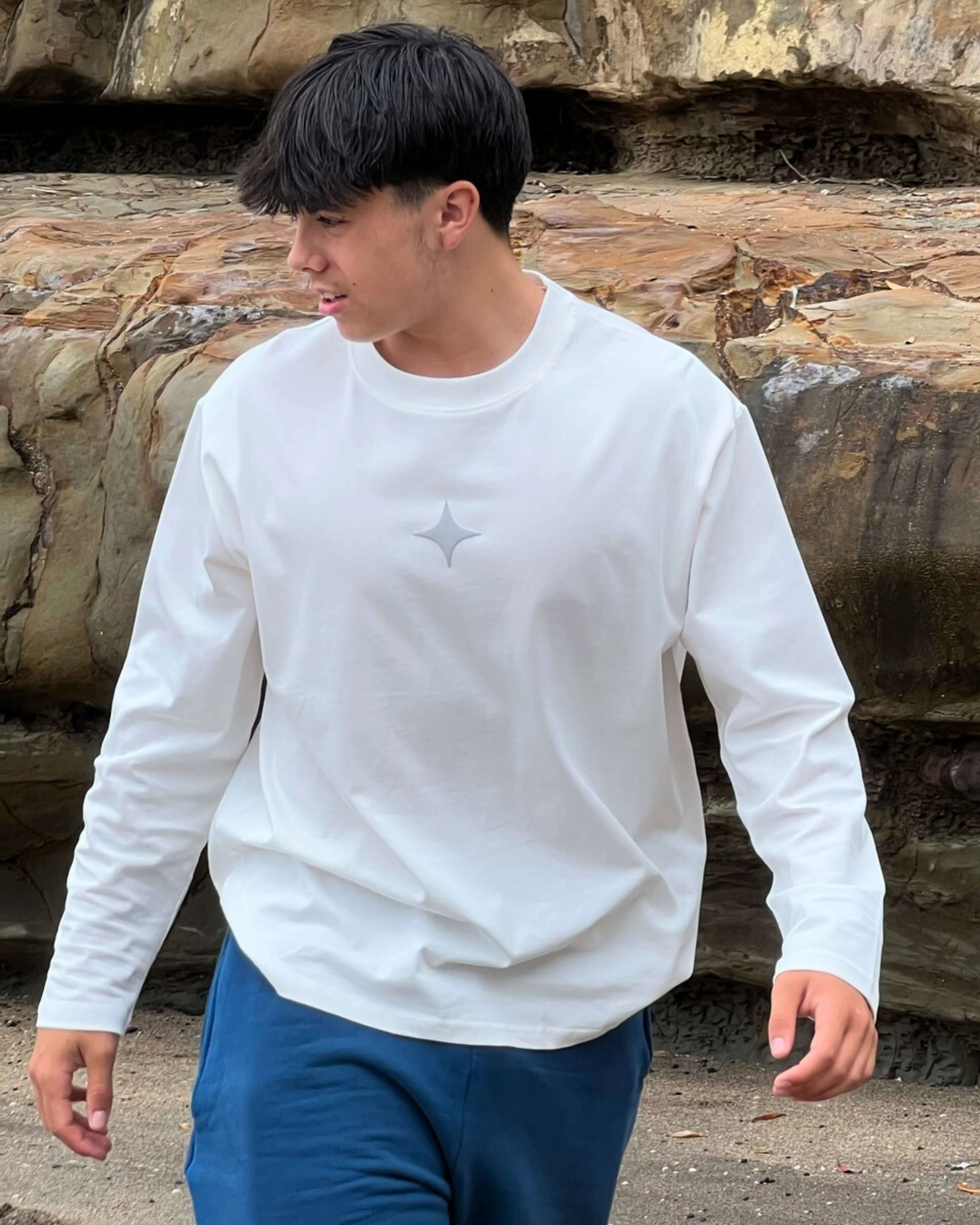 Model wearing Sanity Cloud White Long Sleeve Tee, showcasing comfort and style in a relaxed outdoor setting.