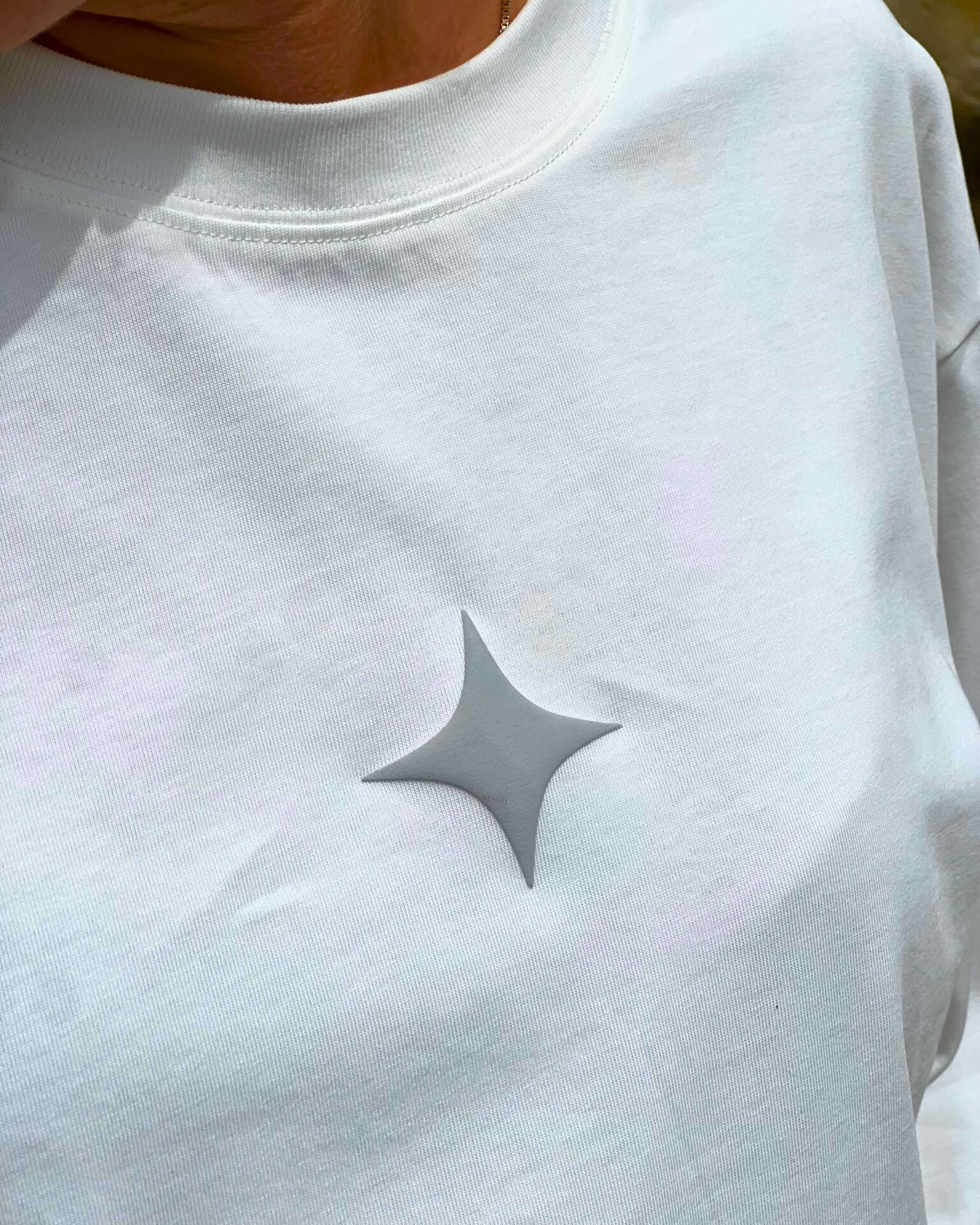 Close-up of a cloud white long sleeve tee featuring a subtle gray star logo on the chest.