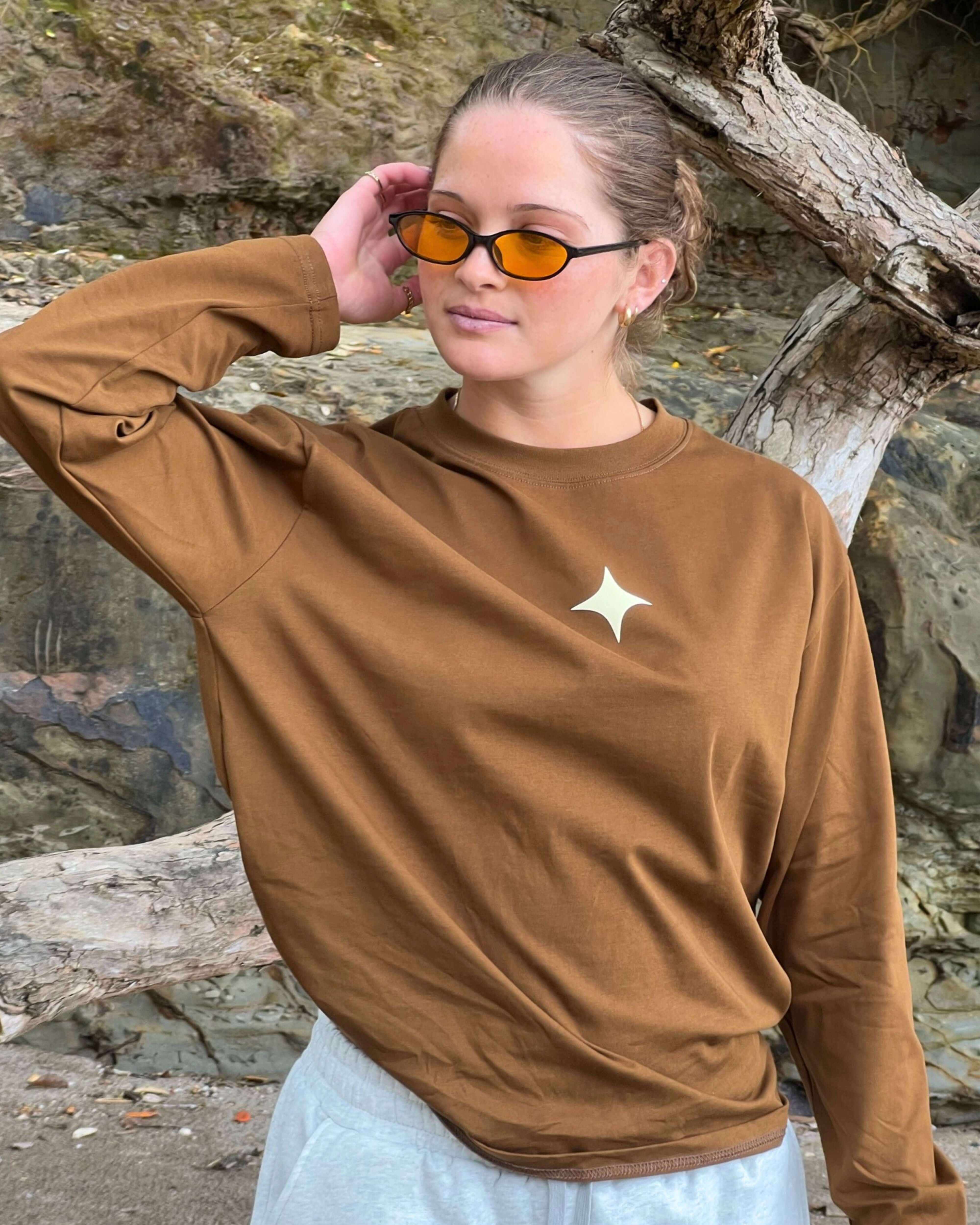 Model wearing Sanity Mocha Long Sleeve Tee with star detail, styled casually outdoors.
