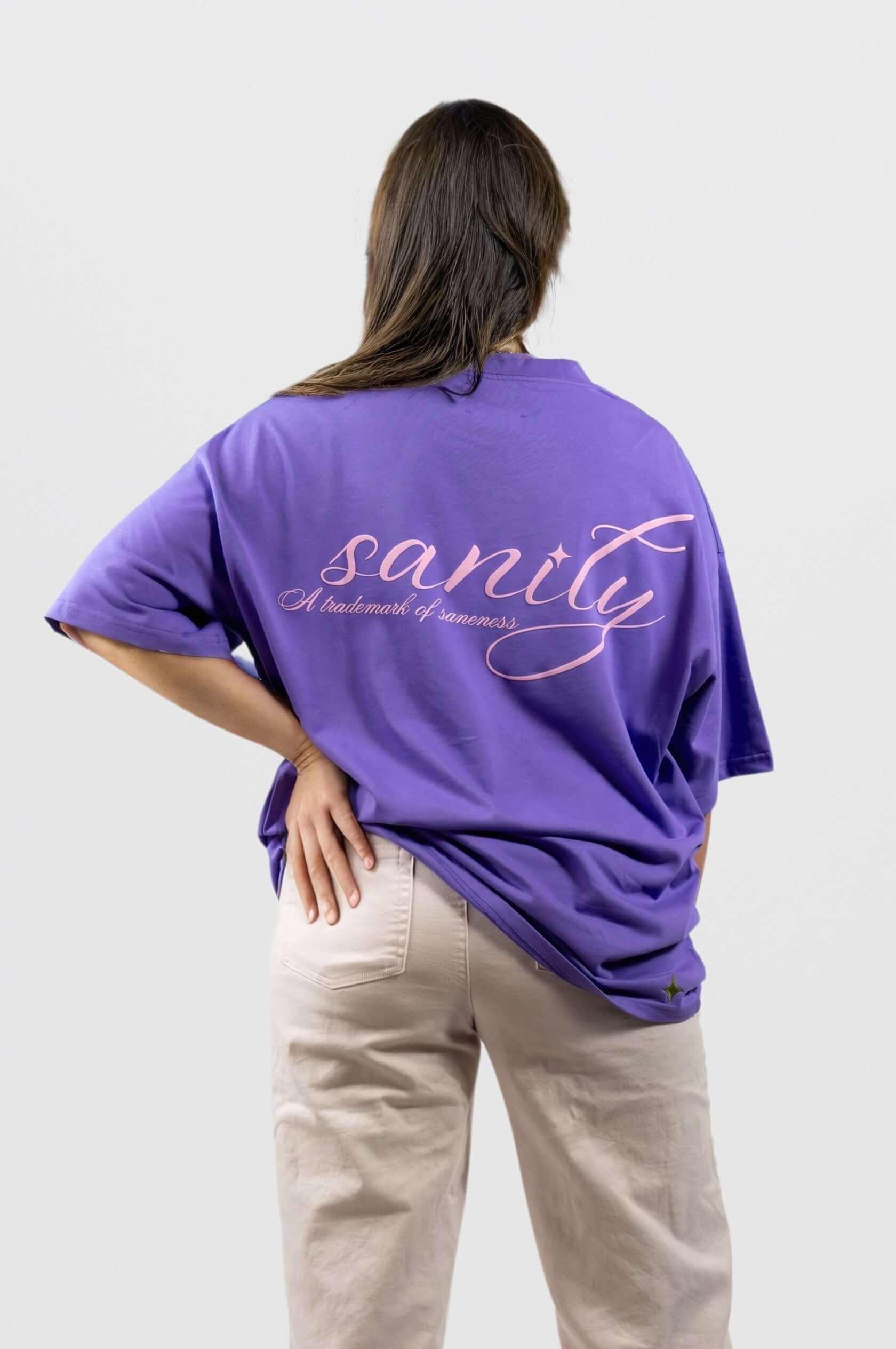 Back view of purple Sanity tee with light pink print and oversized fit, showcasing stylish design and comfort.