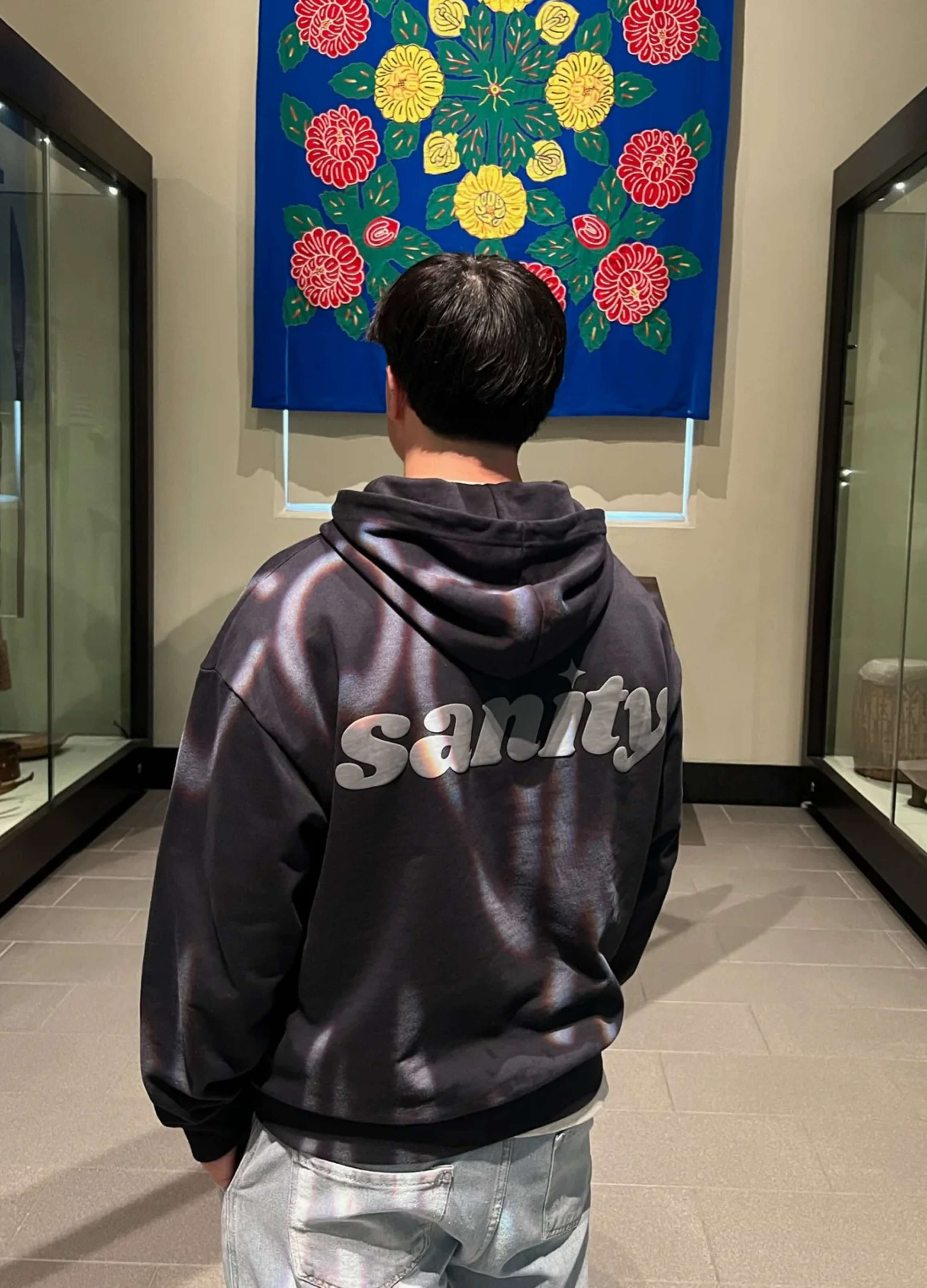 Back view of a person wearing the Sanity Midnight Zip-Up hoodie in heavyweight cotton with grey puff print.