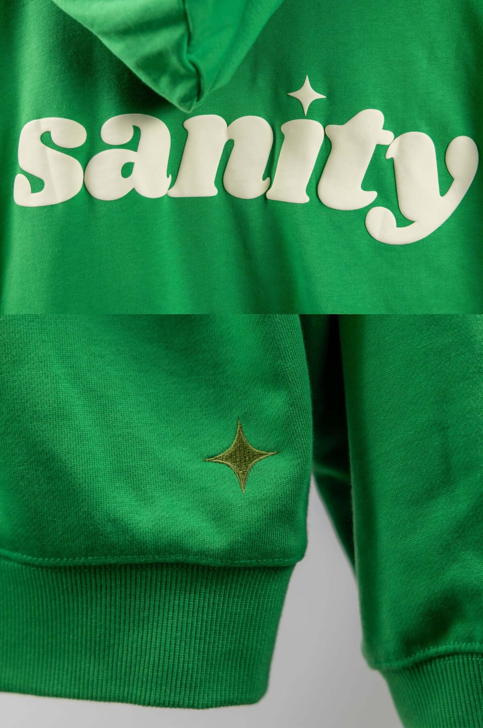 Close-up of Sanity green zip-up hoodie featuring white print and signature embroidery detail.