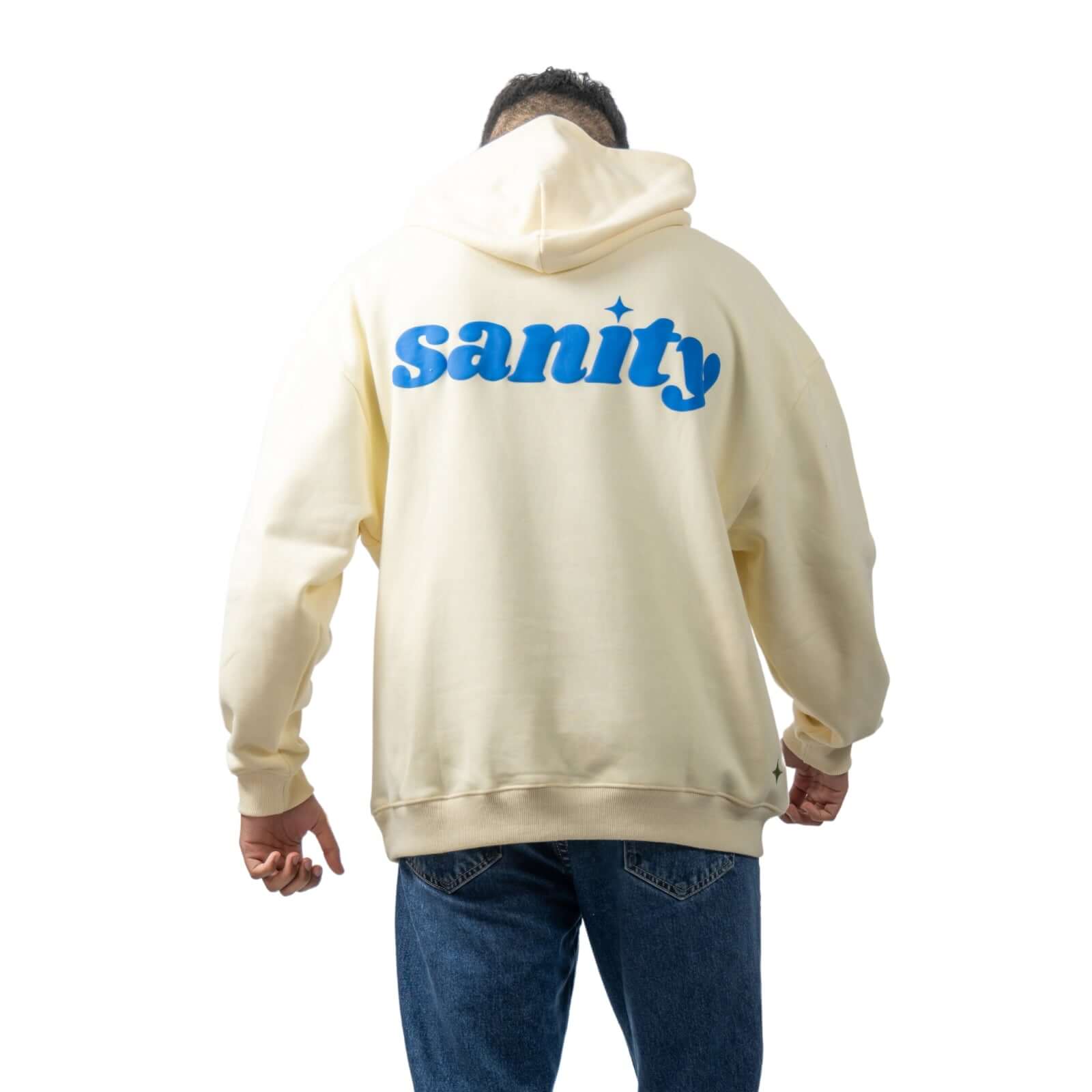 Model wearing cream oversized Sanity hoodie with blue print on back, showcasing signature embroidery.