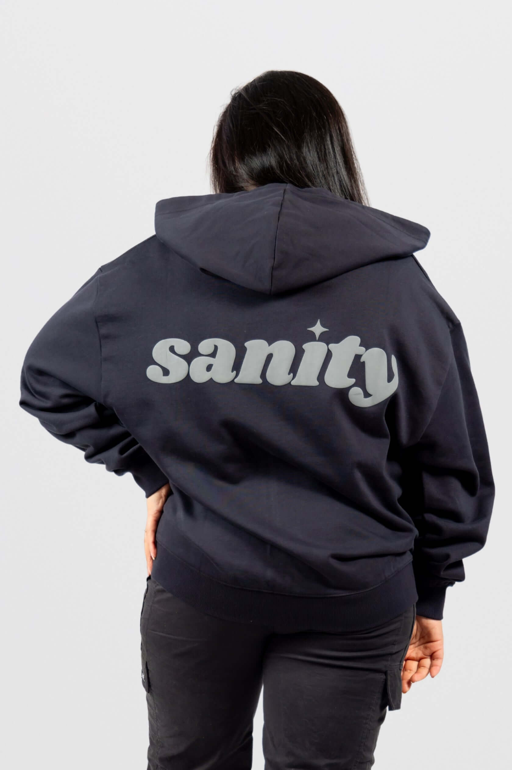 Model wearing the Sanity Midnight Zip-Up hoodie, showcasing the grey puff print on the back against a black background.