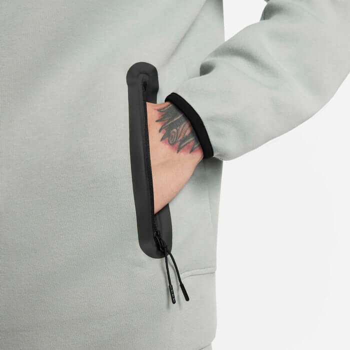 Close-up of Nike Tech Fleece Windrunner Hoodie in Mica Green showcasing zippered pocket and sleek design.