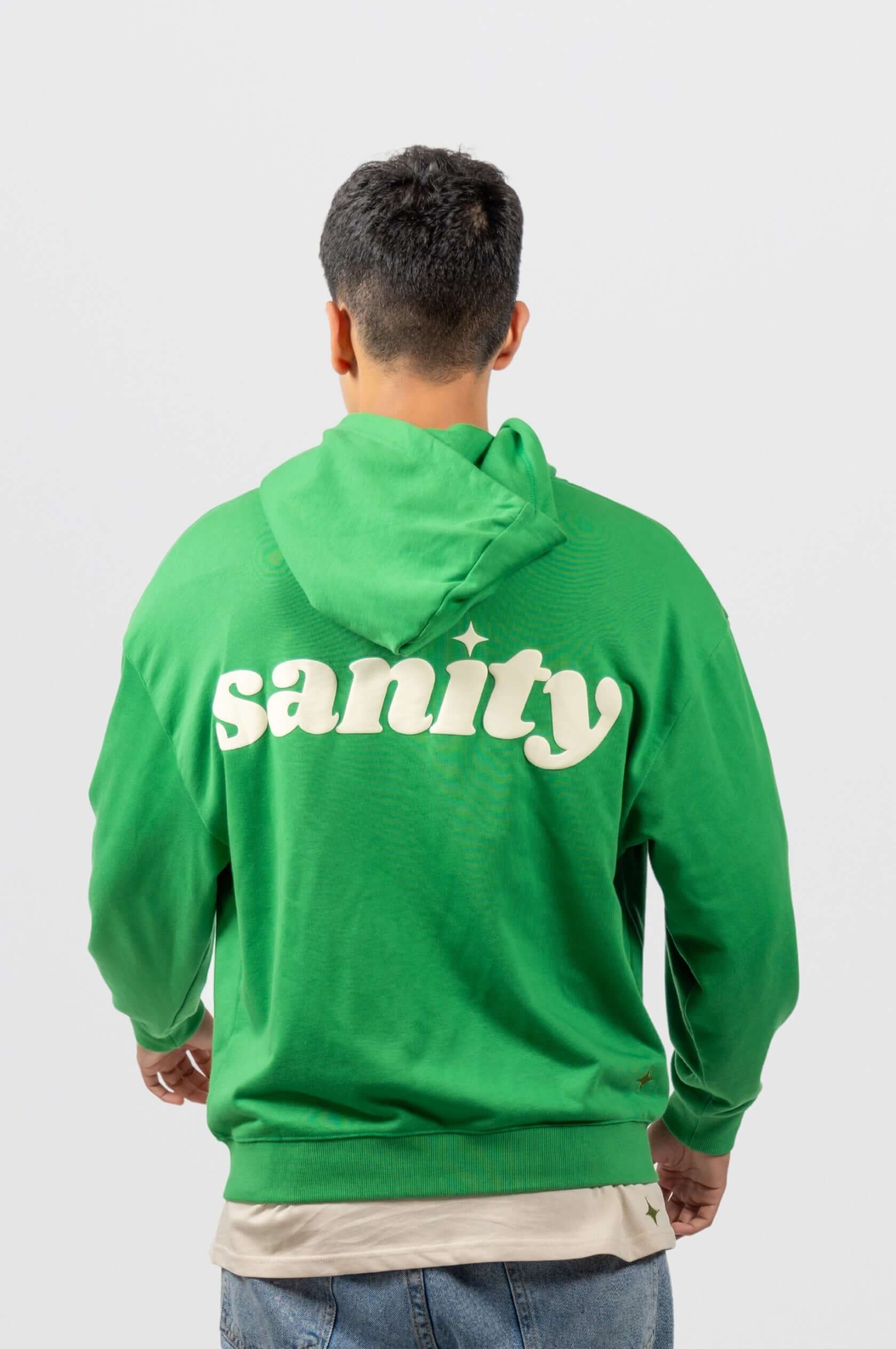 Green zip-up hoodie with 'sanity' print on the back, showcasing a comfortable oversized fit for stylish casual wear.