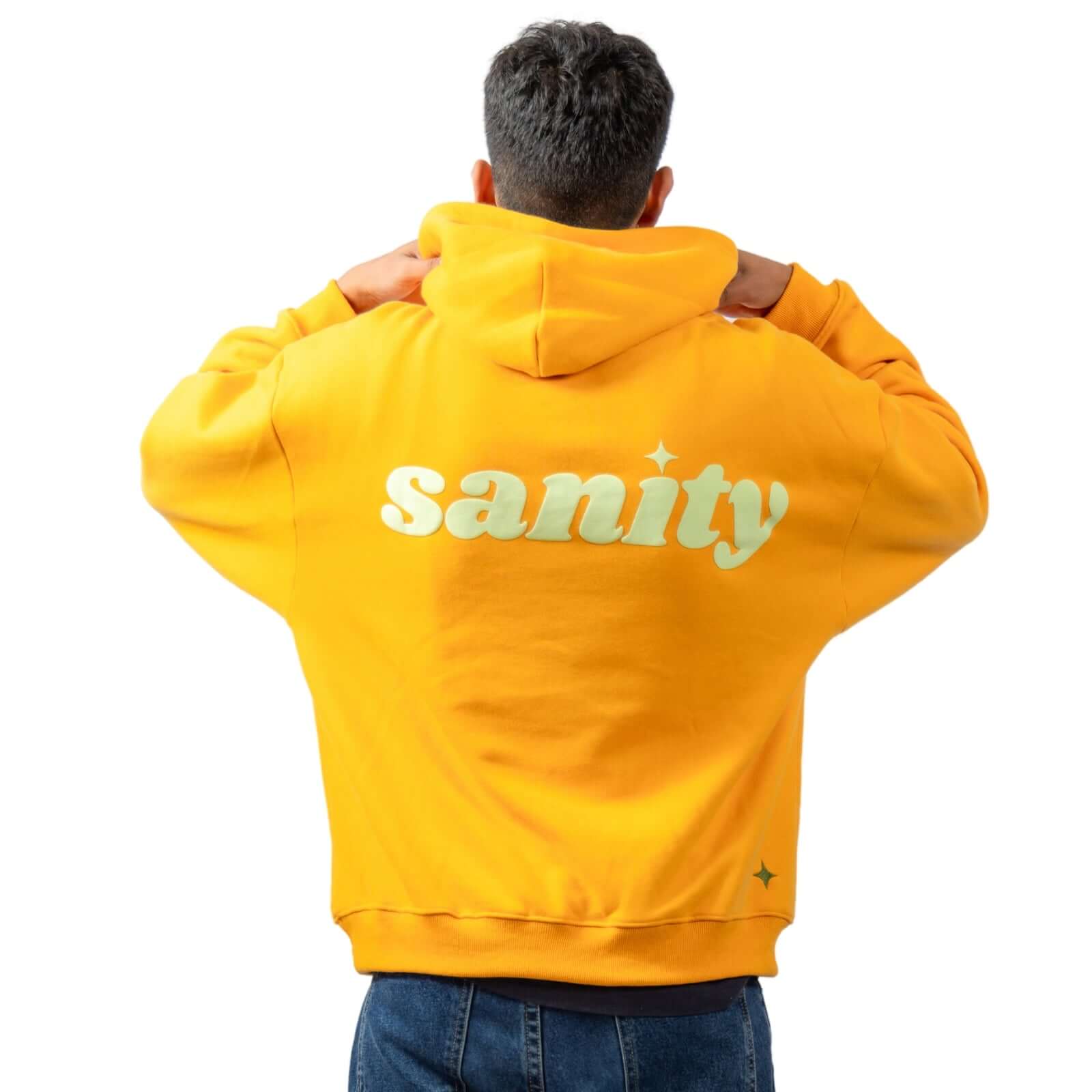 Model wearing a yellow Sanity hoodie with the brand name printed on the back, showcasing its casual and stylish design.