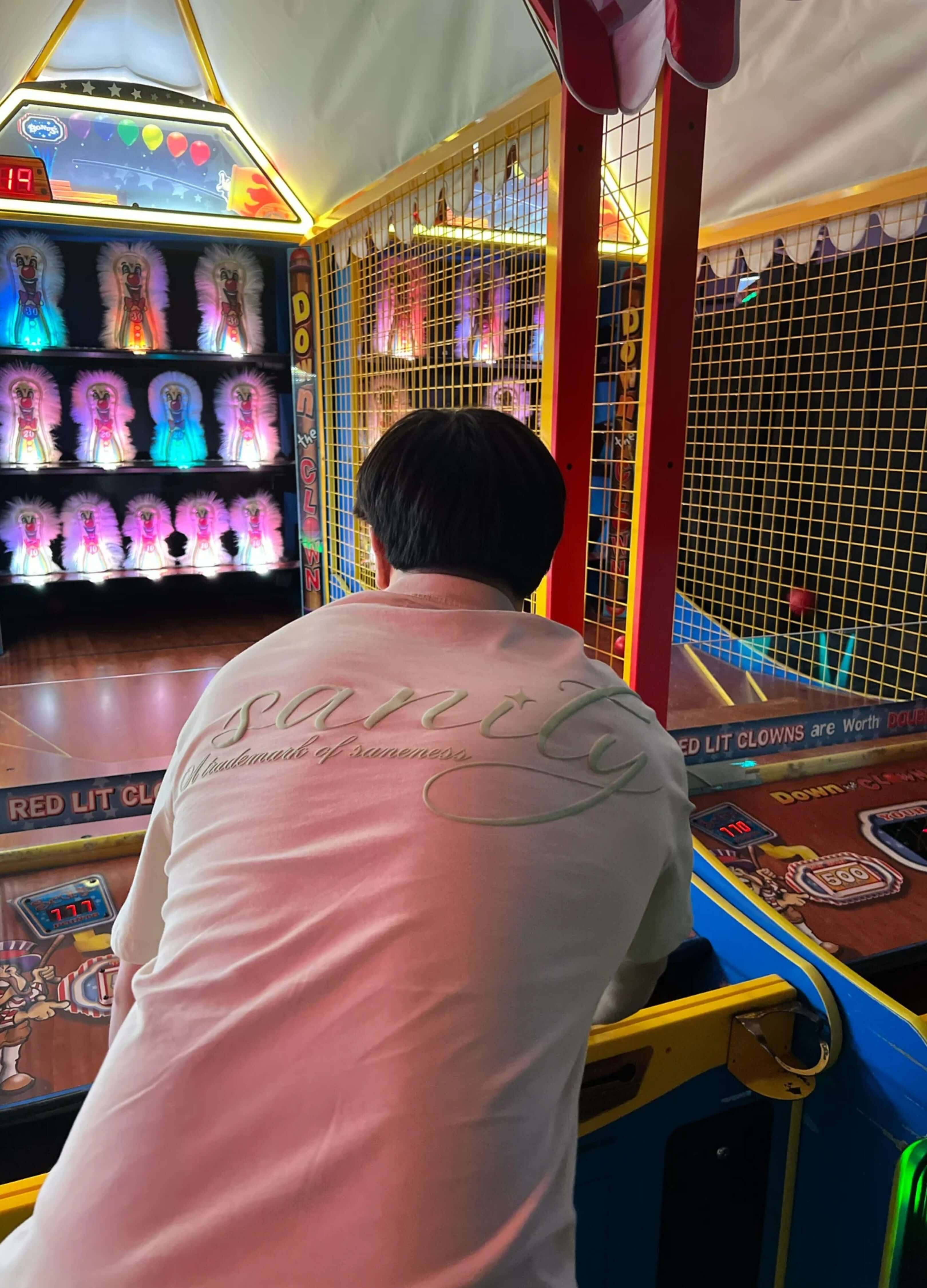 Person playing arcade game wearing off-white Sanity mint tee, showcasing relaxed fit and signature embroidery.
