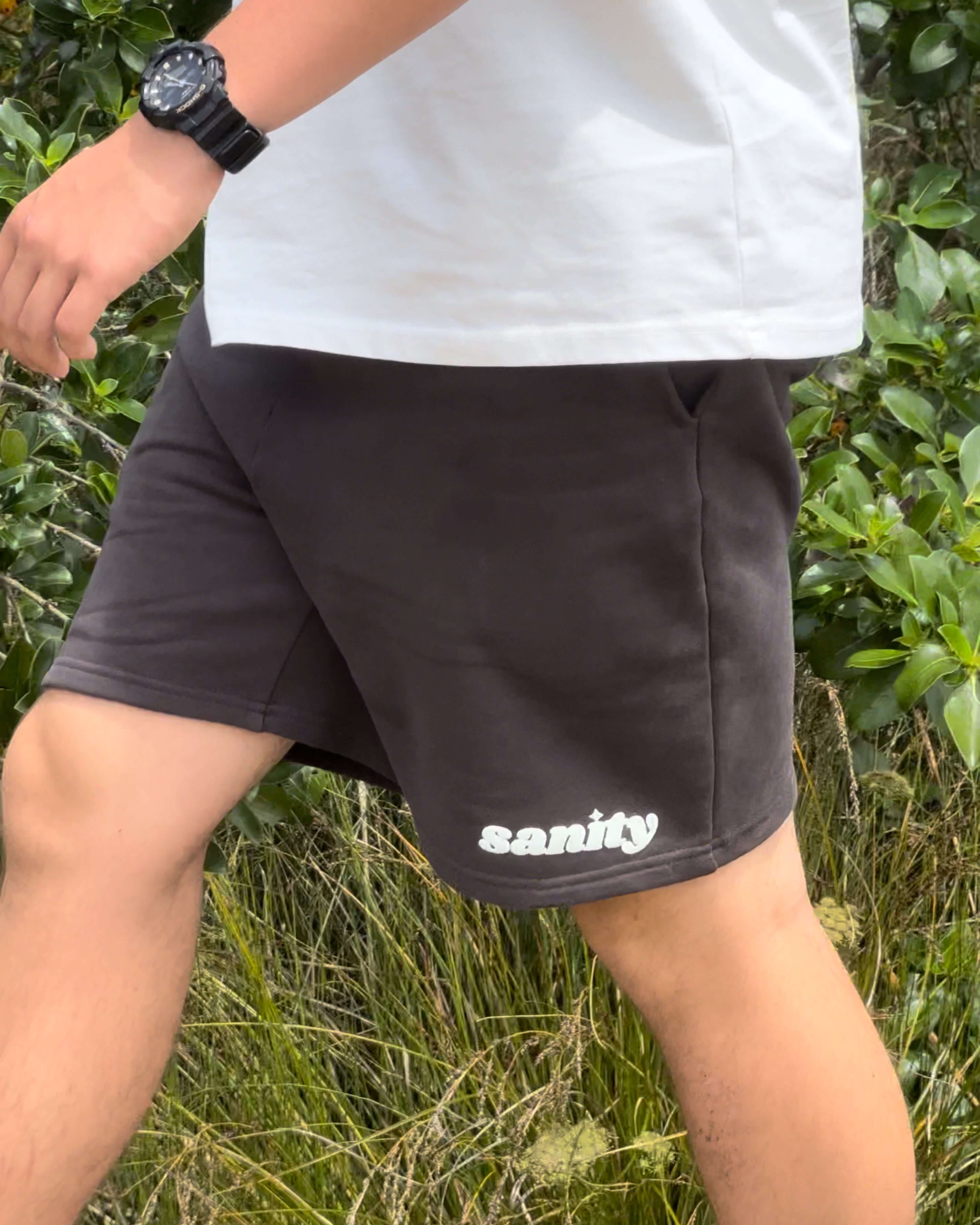 Man wearing Sanity Shadow Men's Shorts in deep charcoal, showcasing comfort and style for casual outings.