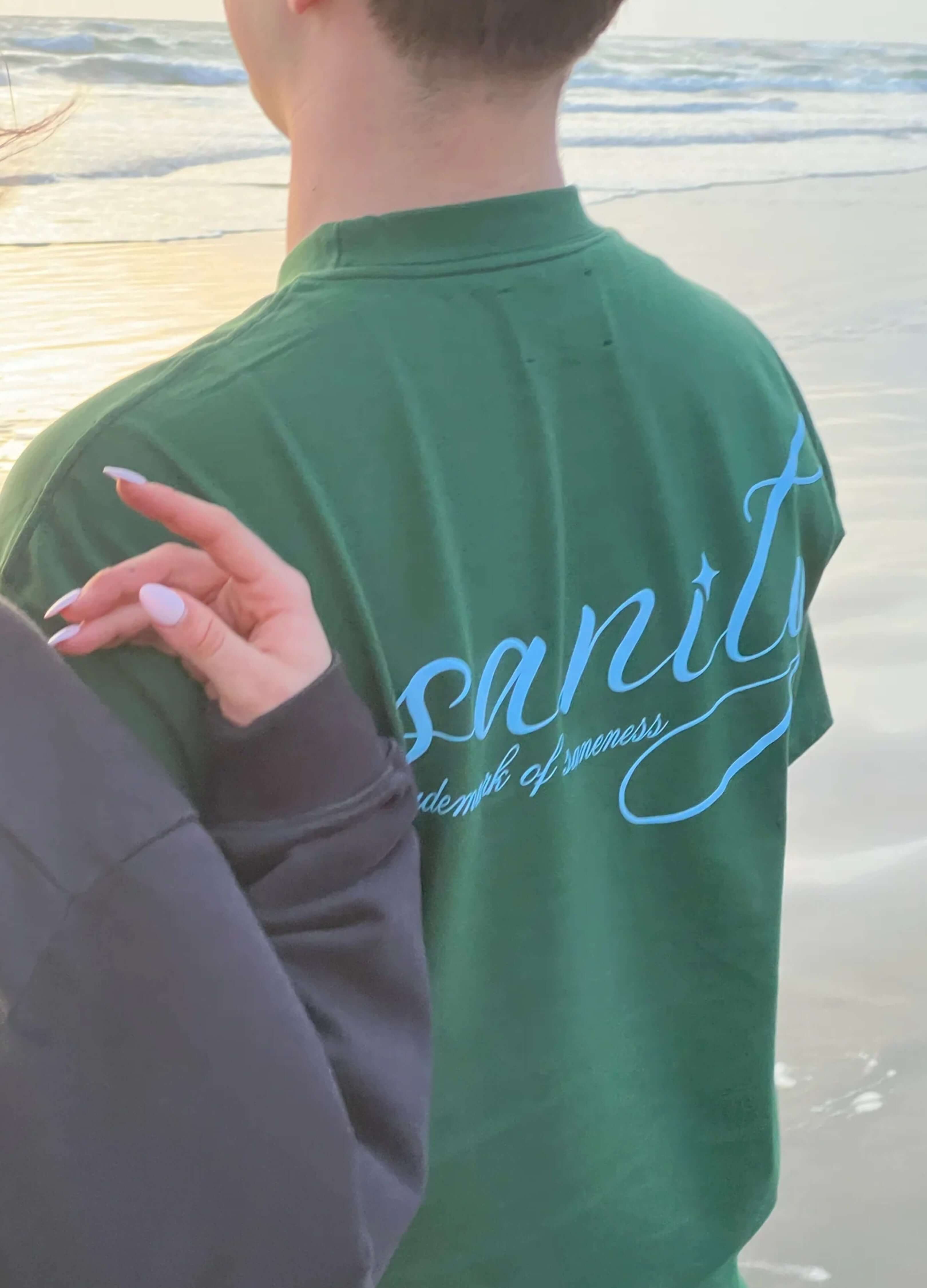 Unisex forest green Sanity tee with light blue print, perfect for a laid-back beach look.