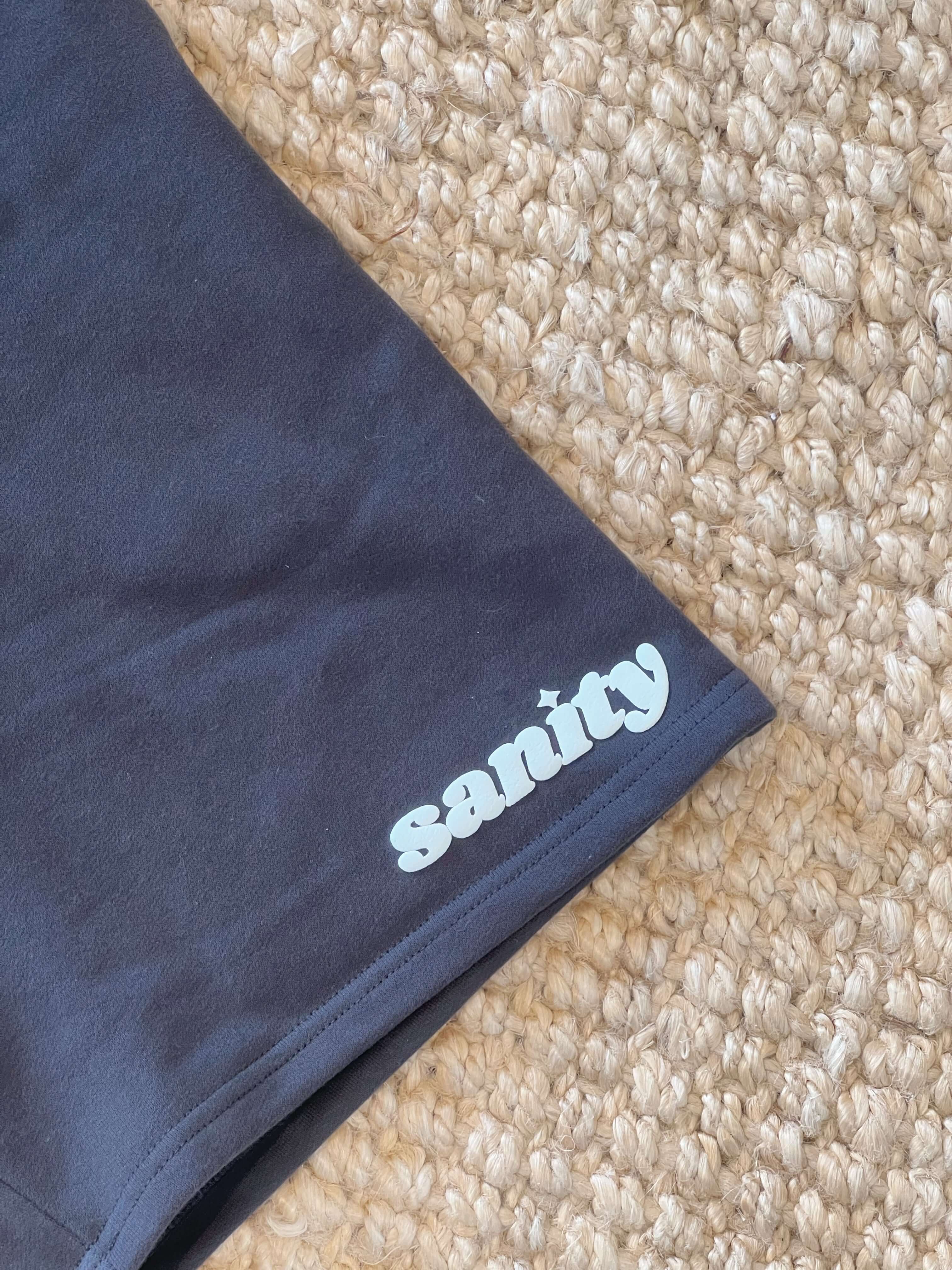 Close-up of Sanity branded shadow men's shorts in deep charcoal fabric, showcasing premium cotton and a subtle draw cord detail.