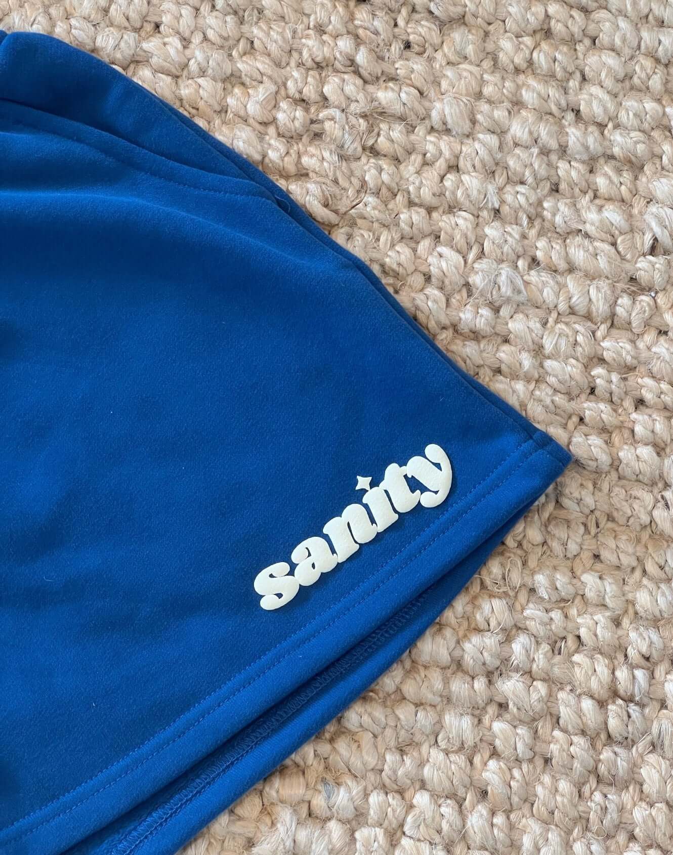Close-up of Sanity Deep Sea Women's Shorts in rich navy featuring a playful brand logo.