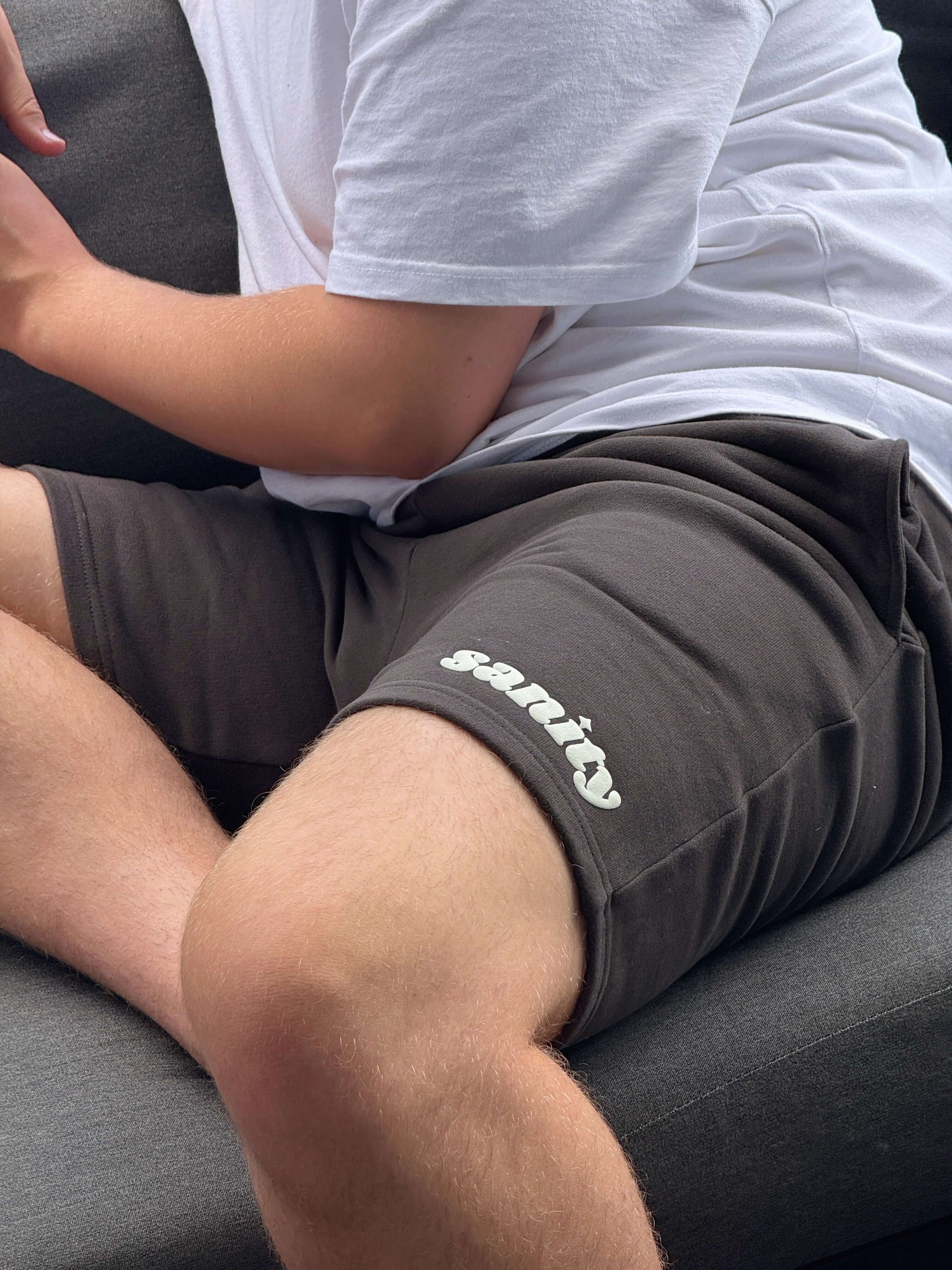Model wearing Sanity Shadow Men's Shorts in deep charcoal, showcasing comfort and sleek style.