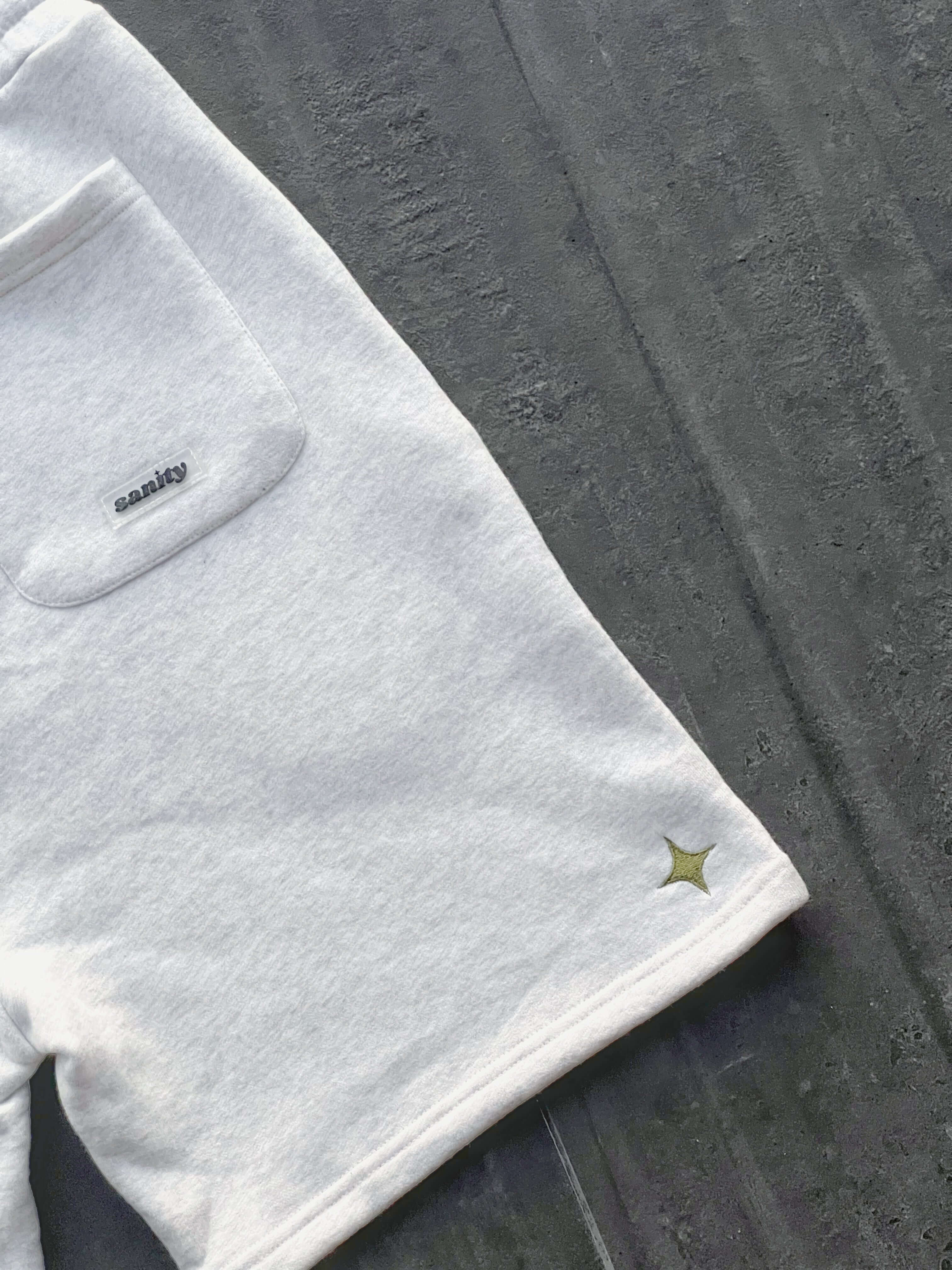 Close-up of Sanity Snow Men's Shorts in white, featuring a back pocket and logo detail.