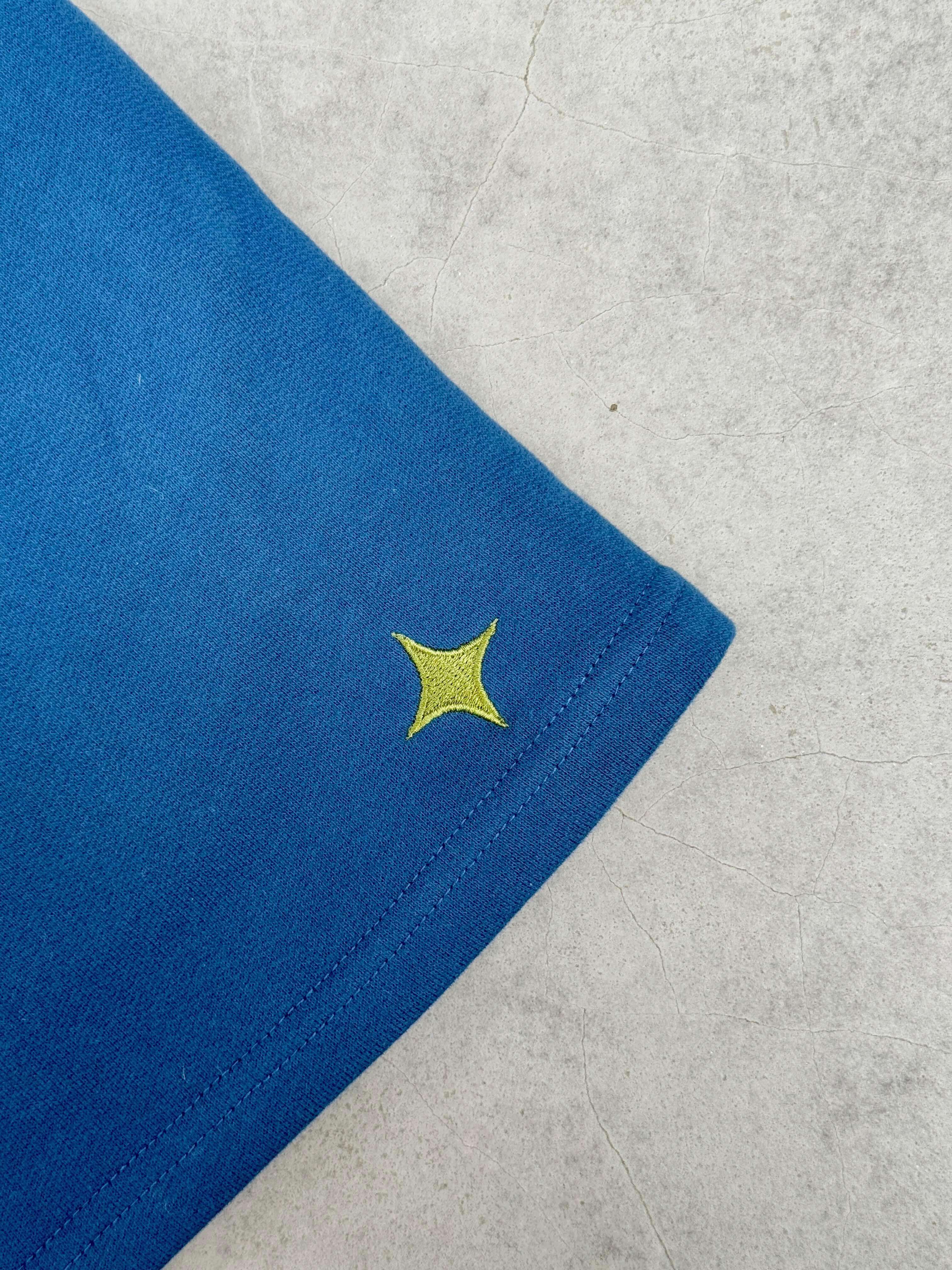 Close-up of the blue fabric of Sanity Deep Sea Men's Shorts with yellow logo detail.