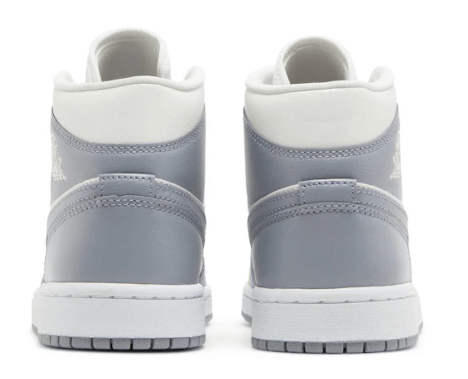 Back view of women's Jordan 1 Mid Stealth sneakers in grey and white, showcasing sporty design and premium materials.