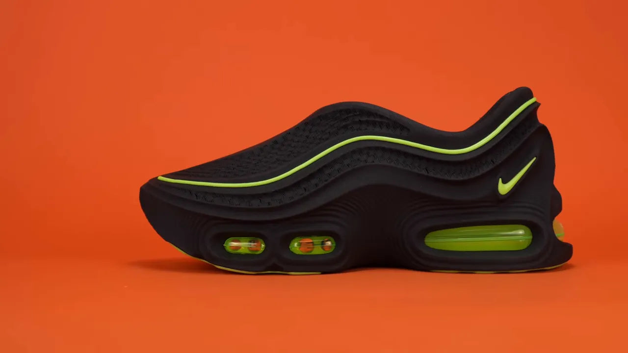 Black slip-on shoe with neon green piping and visible air units on orange background